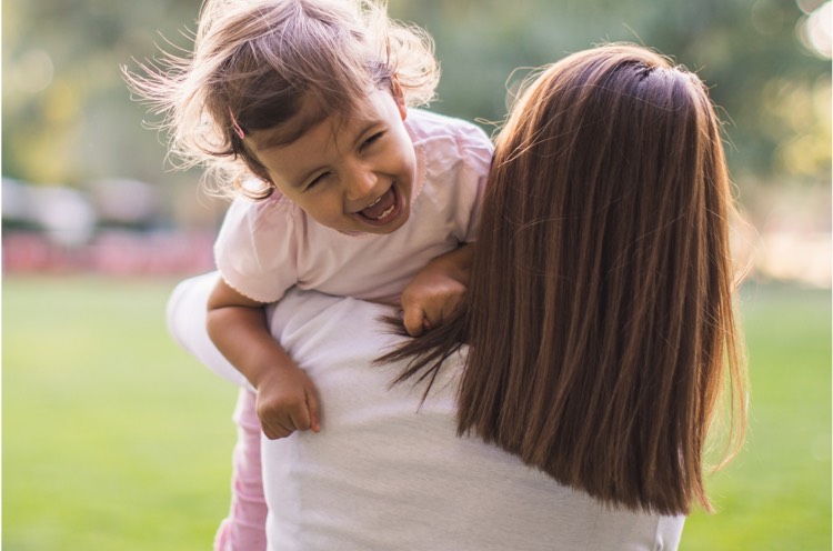 A nanny carrying a smiling child to a park