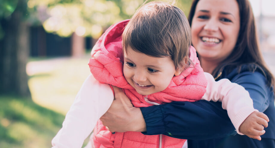 A child care provider playing with a small child at a park
